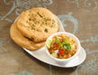 plate of spiced chickpea chole with soft butter-brushed kulchas
